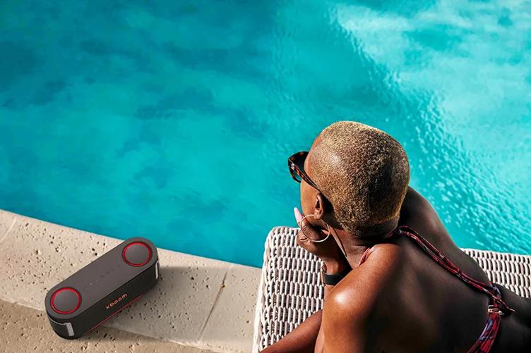 Woman sitting poolside with the xboom Bounce speaker in the forefront
